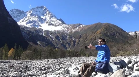 Hiker taking self portrait with a cell phone in the snow mountain area Stock Footage 43505333
