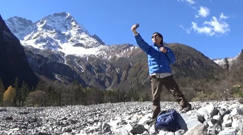 Hiker taking self portrait with a cell phone in the snow mountain area Stock Footage 43505499