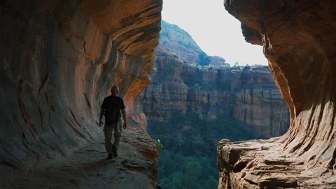 A hiker taking in the view from a sandstone cave Stock Footage 249124540