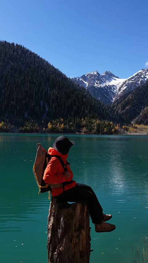 Hiker throwing a stone into a beautiful mountain Issyk's lake, Kazakhstan Видео 344589390