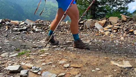 Hiker trekking close-up rear view across a rocky mountain trail Stock Footage 343768586