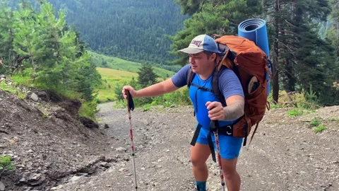 Hiker trekking front view uphill on a rough mountain road Stock Footage 343773455