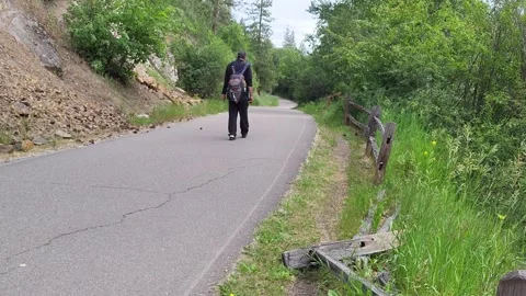 Hiker Trudging Up Hill on Paved Trail  Along River In Park Wearing Daypack 스톡 동영상 339973529