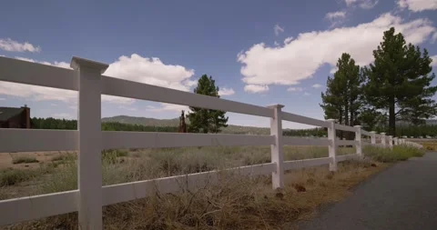 Hiker Walking Along a Rural Path by a White Fence Stock Footage 323354444