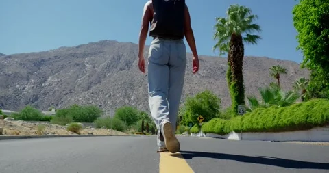 Hiker Walking Down Deserted Road in Mountainous Landscape Stock Footage 323347289