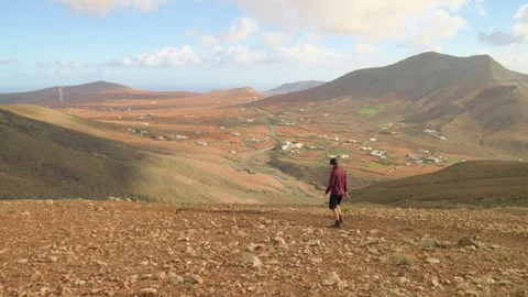 Hiker Walking Down Mountain Slope Overlooking Valley Landscape Wide Shot 스톡 동영상 331212974