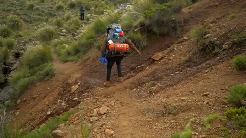 A hiker walking down a sandy mountain slope Stock Footage 254797990