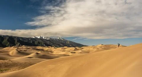 Hiker Walking Down The Steep Edge of Sand Dune Foto stock