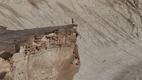 Hiker walking to the edge of a cliff in a dramatic desert canyon of Bozjyra Stock Footage 322110476