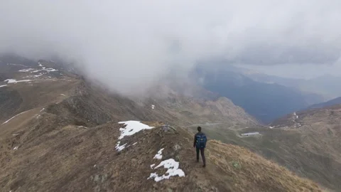 Hiker walking on the peak of the mountain while snowing Stock Footage 215915290