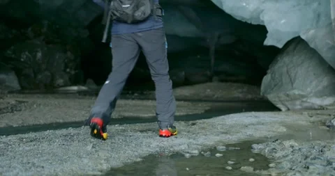 Hiker walking through a beautiful blue glacier ice cave 库存影片 339249746