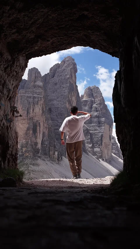 Hiker walking through a dark cave towards the tre cime di lavaredo Video stock 320498302