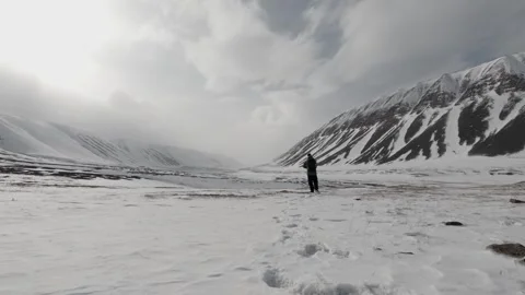 Hiker Walking Through a Snow Covered Arctic Valley in Svalbard, Norway 스톡 동영상 339277843