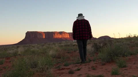 Hiker walking towards monument valley at sunrise Stock Footage 334852942