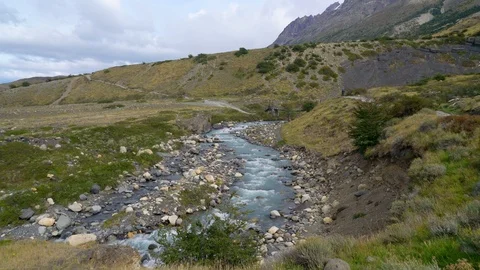Hiker walking a track next to a small river at the Torres del Paine Stock Footage 109508570