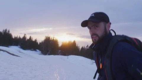 A hiker walks actively in the snow at sunset, in the Swiss Alps Stock Footage 229670026