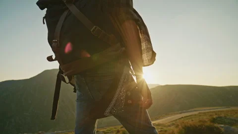 Hiker walks along a mountain trail at sunset preparing for an adventure in the Stock Footage 345632595
