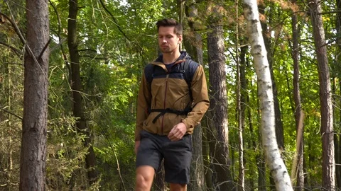 A hiker walks down a pathway through a forest 스톡 동영상 109332777
