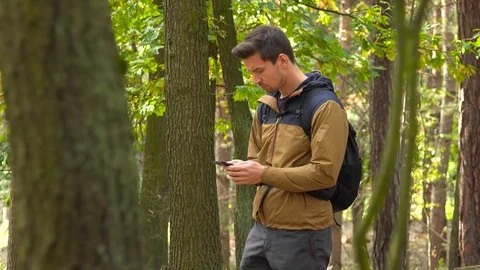 A hiker walks through a forest, stops, looks around and on a map on a Vídeos de archivo 109333227