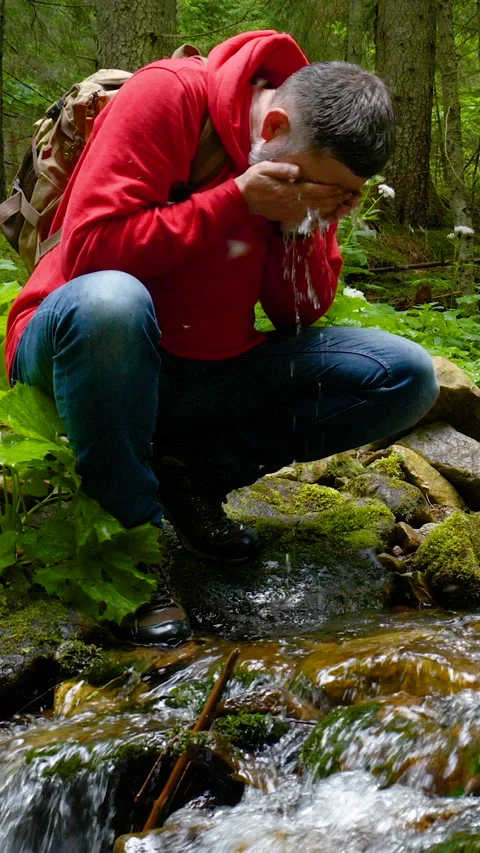 Hiker washing face in cold mountain stream 库存影片 334333337