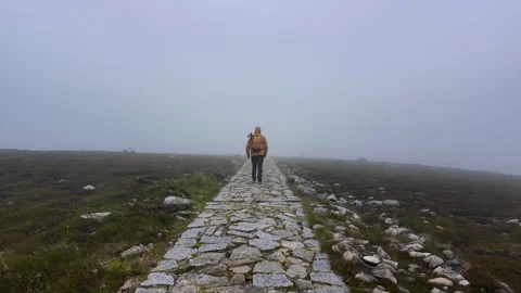 Hiker in yellow jacket walking into thick fog on mountain path. Stock Footage 340991049