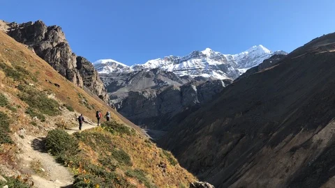 Hikers with backpack at Annapurna Circuit hike along steep mountains Stock Footage