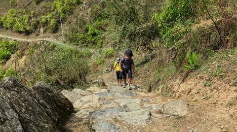 Hikers with backpack go up in mountain road. Himalayas Nepal nature HD video Stock Footage 64828250