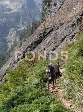 Hikers climbing steep mountain trail Stock Photos