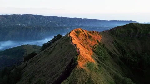Hikers Crossing Dramatic Volcanic Ridgeline in Golden Morning Light Rising Видео 335177004