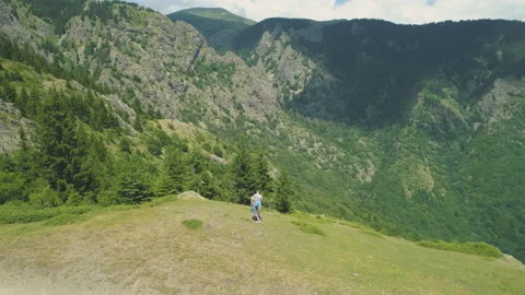 Hikers enjoying the view from mountain summit. Panoramic view of forested Stock Footage 158151487