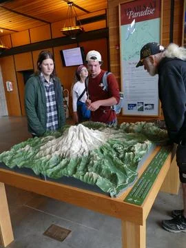 Hikers examining a 3D model of Mount Rainier at the Paradise Jackson Visito.. Stock-Fotos