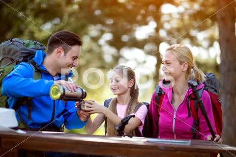 Hikers father gives drink to her child girl. Stock Photos