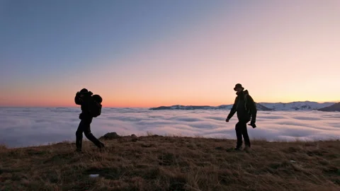 Hikers at Mountain's Edge with Clouds Below at Sunrise Stock Footage 328157198