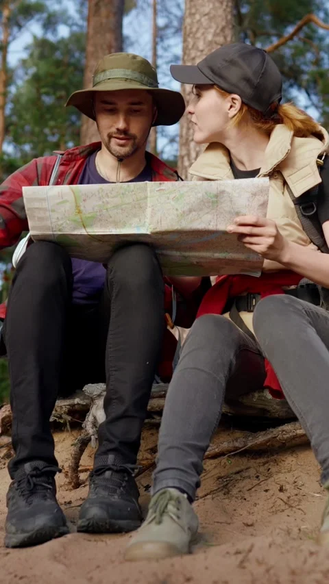 Hikers with paper map sitting in forest halt in woodland, vertical video. Happy Stock Footage 294738022