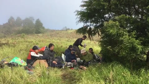 Hikers Resting on a Grassy Mountain Meadow, Mount Prau, Indonesia. 動画素材 344314855