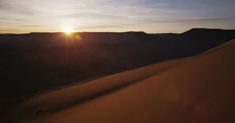Hikers running down red sand dune with sun setting in slow motion Stock Footage 64331080