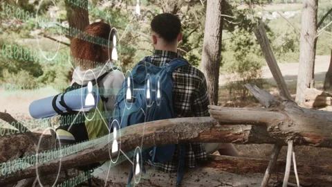 Hikers sitting on log, binary code sliding from left overlaying packs Stock Footage 333610258