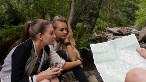 Hikers study the map of the area in a camping near the creek Stock Footage 78642429