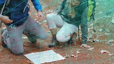Hikers studying paper map, using GPS and turning map while faint grid shows Stock Footage 333526492