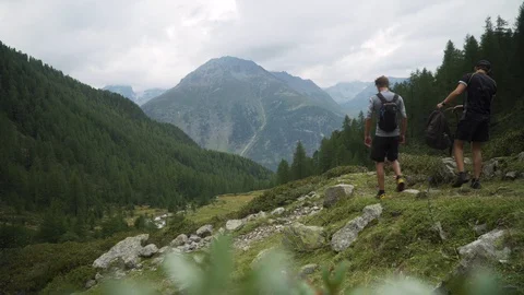 Hikers taking a break, sitting down and resting in green rocky meadows, 4K Stock Footage 129612757