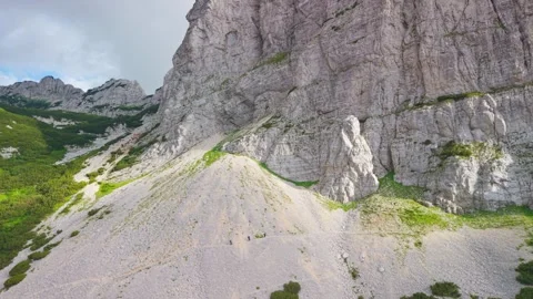 Hikers traversing a scree path along massive limestone cliffs on the approach 库存影片 341837125
