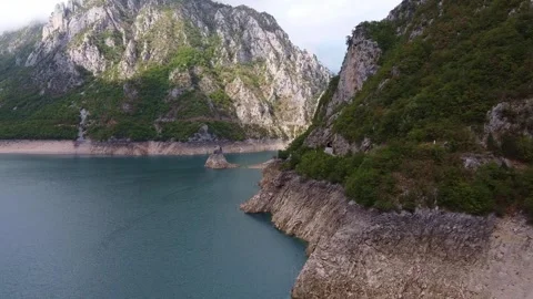 Hikers traversing steep cliffs above a mountainous lake valley in Montenegro Stock-Footage 342775370