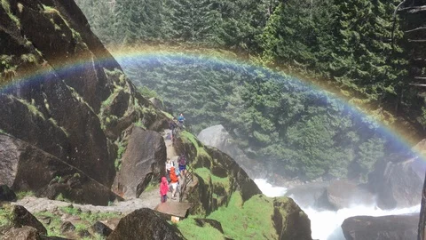 Hikers under a rainbow mist from waterfall on hiking trail Stock-Footage 90276971