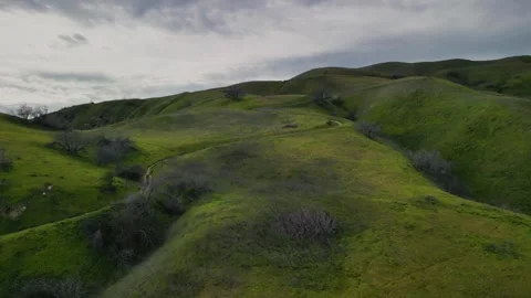 Hikers walking down Grassy Hillside Trail Overcast A Stock Footage 242040105