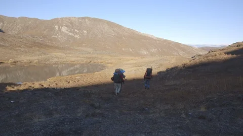 Hikers Walking Down Hillside Towards Lake Arrigetch Peaks Stock Footage 121640302