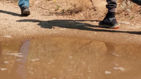 Hikers Walking Past Puddle on Dirt Trail Stock Footage 345540736