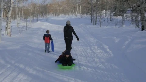 Hiking back up the hill on pulling kids on a sled. Stock Footage 72249245