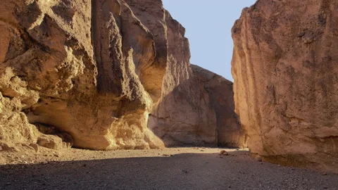 Hiking between big rocks lit by golden sunlight at the Natural Bridge trail Stock Footage 217580685