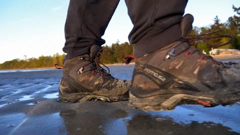 Hiking boots walking on a sandy beach in slow motion close up. Stock Footage 129659436