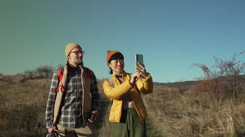 Hiking couple checking smart phone for directions in the mountains Video stock 320461135